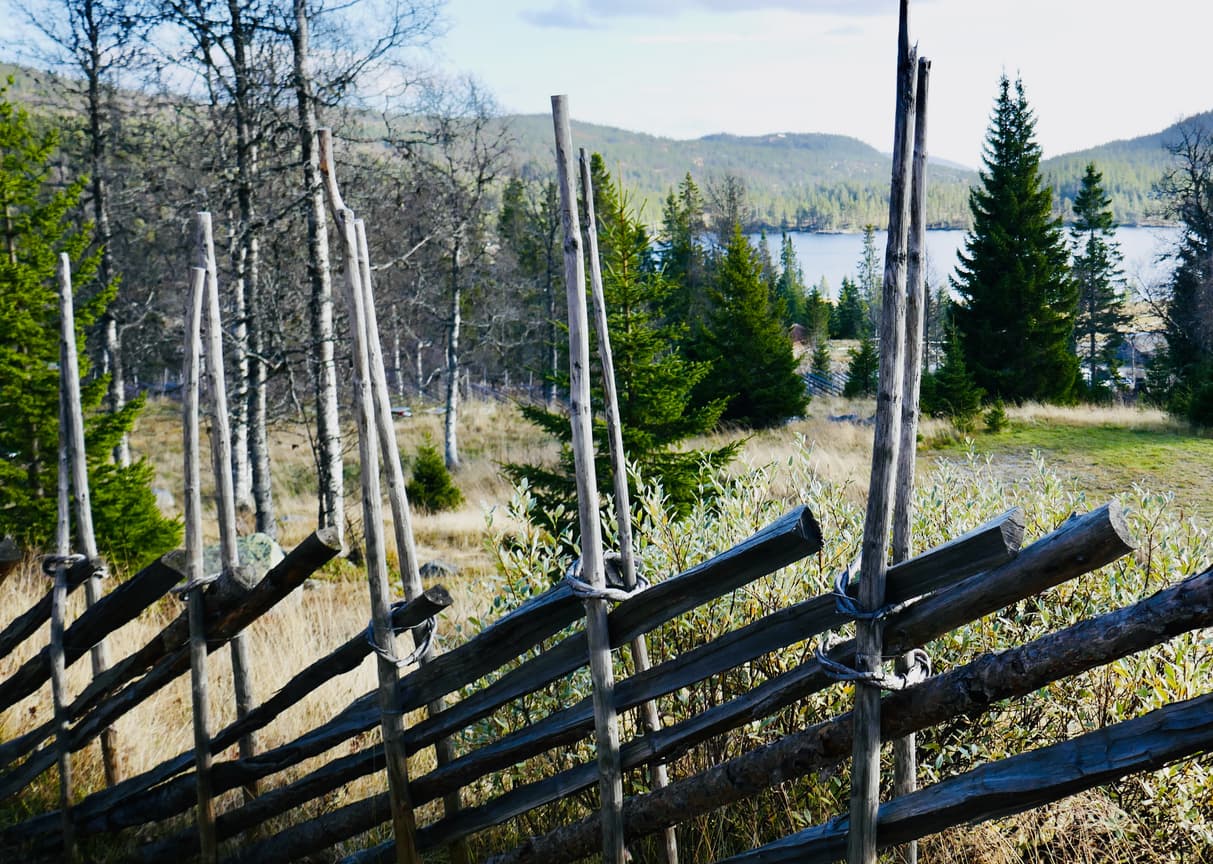 Tradisjonell norsk skigard av tre med skråstilte staur foran åpent landskap, fjell og vann, brukt som illustrasjon i artikkel om tomtegrenser.