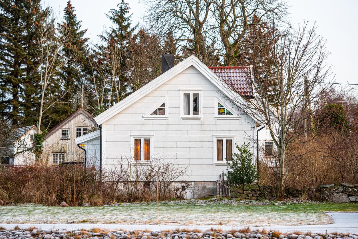 Hvitt trehus med nabohus tett inntil og lett snø på plenen, brukt som illustrasjon i artikkel om bruksrett på eiendom.