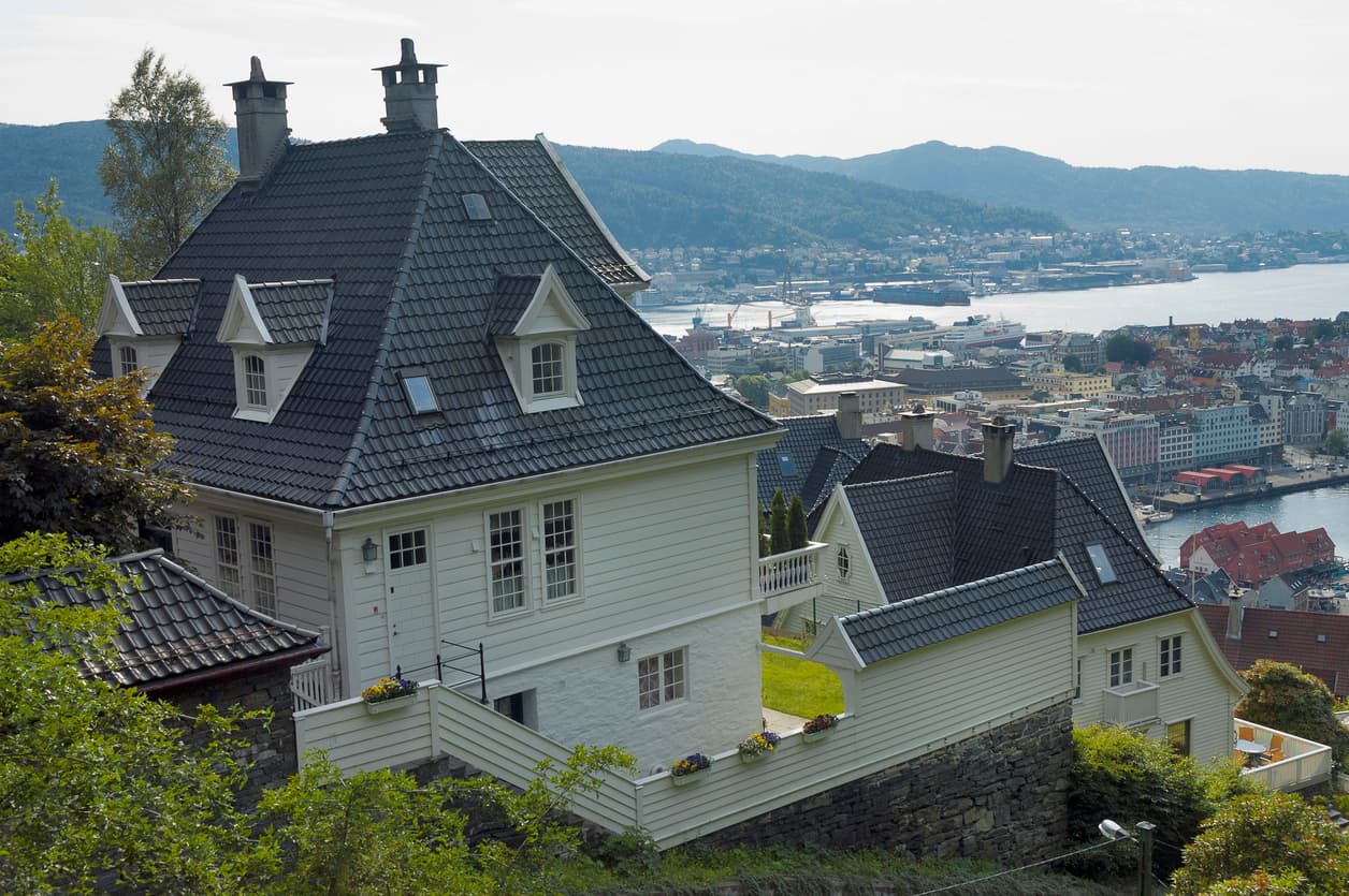 Hvite trehus ligger tett i en bratt skråning over havnebyen Bergen med sjøen nedenfor, som illustrasjon til loven om utsikten.