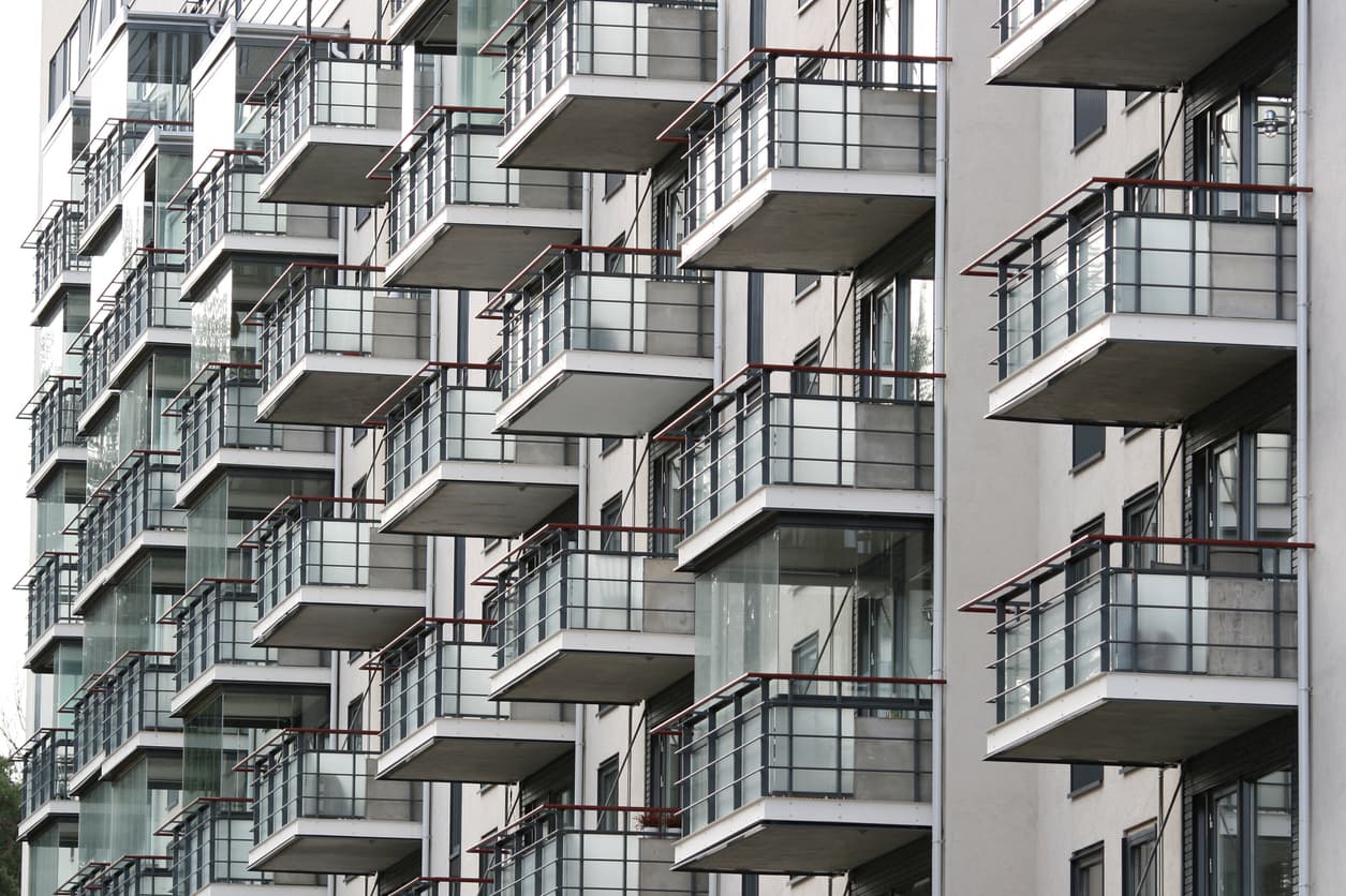Moderne leilighetsbygg med rader av balkonger og glassrekkverk i grå betong, brukt som illustrasjon i artikkel om reklamasjon på nybygg.