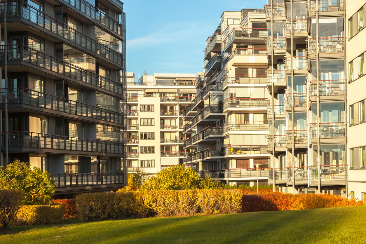 Boligblokker med glassbalkonger og grønt fellesareal, brukt som illustrasjon til en artikkel om borettslag og regler om støy.