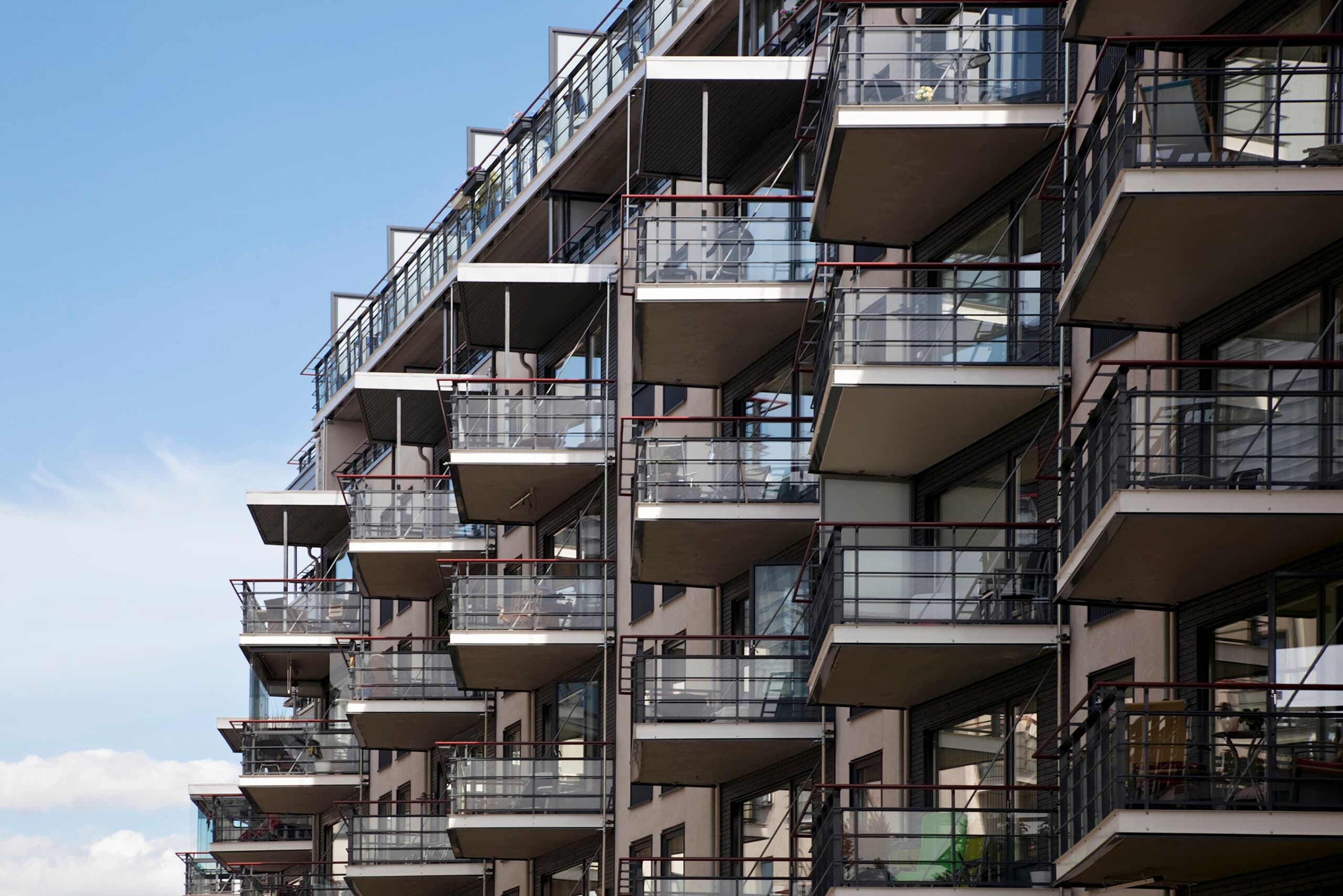 Leilighetsblokk med mange balkonger og metallrekkverk mot blå himmel, brukt som illustrasjon i artikkel om lov om oppføring av bolig og frister for reklamasjon.