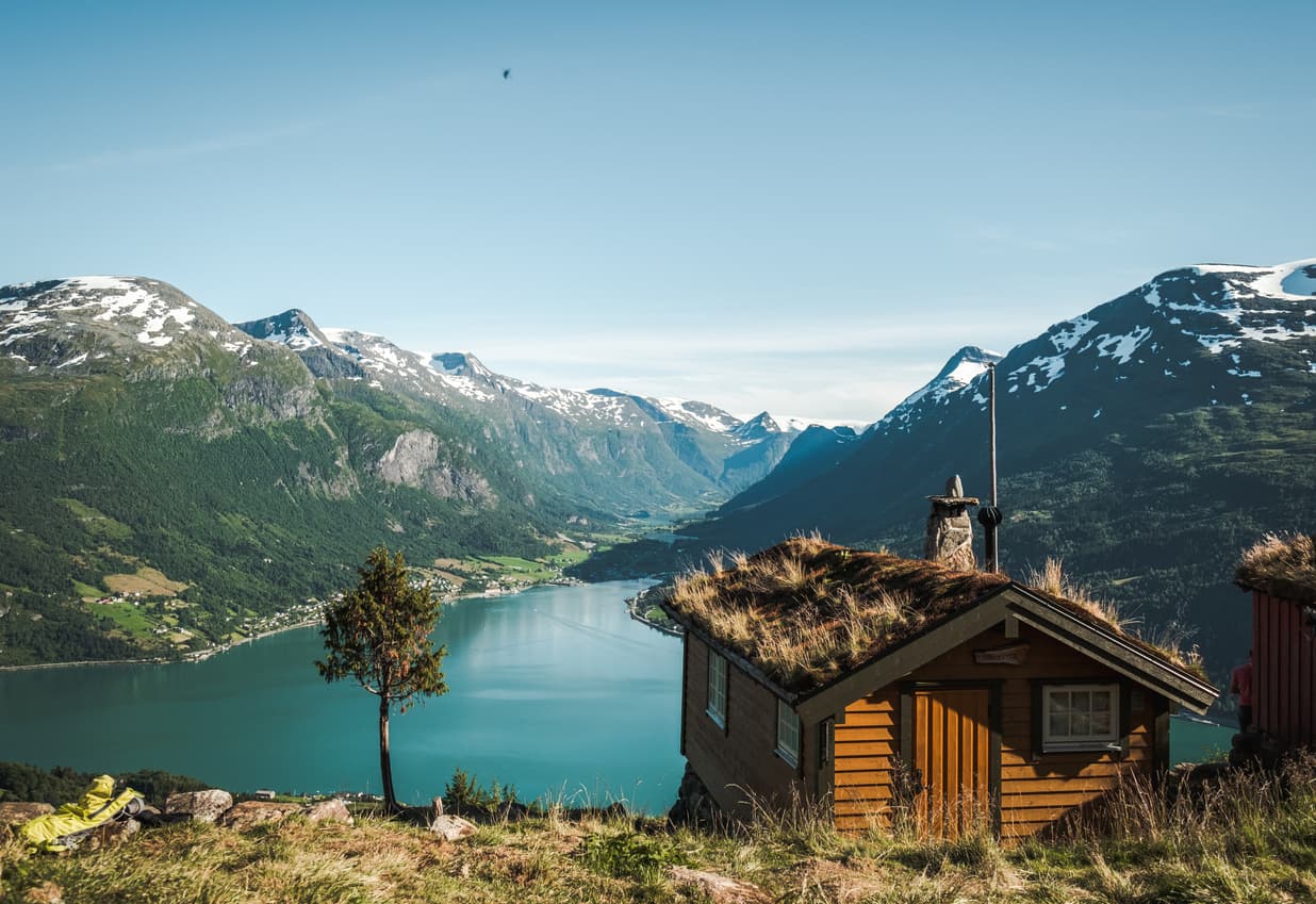 Liten norsk fjellhytte med torvtak og utsikt over fjord, brukt som illustrasjon i artikkel om tvangsoppløsning av sameie.