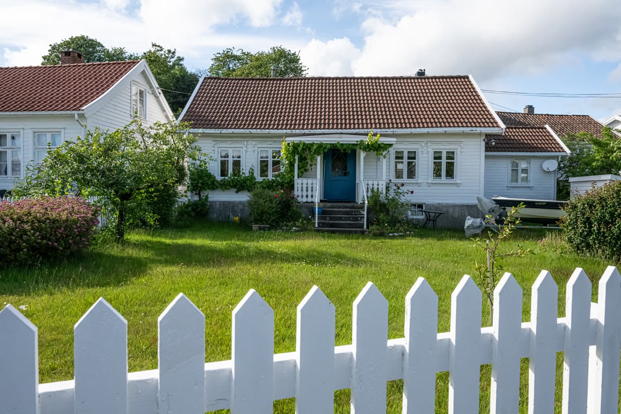 Hvitt stakittgjerde som markerer grensen mellom to naboeiendommer, et typisk eksempel på et lovlig nabogjerde.