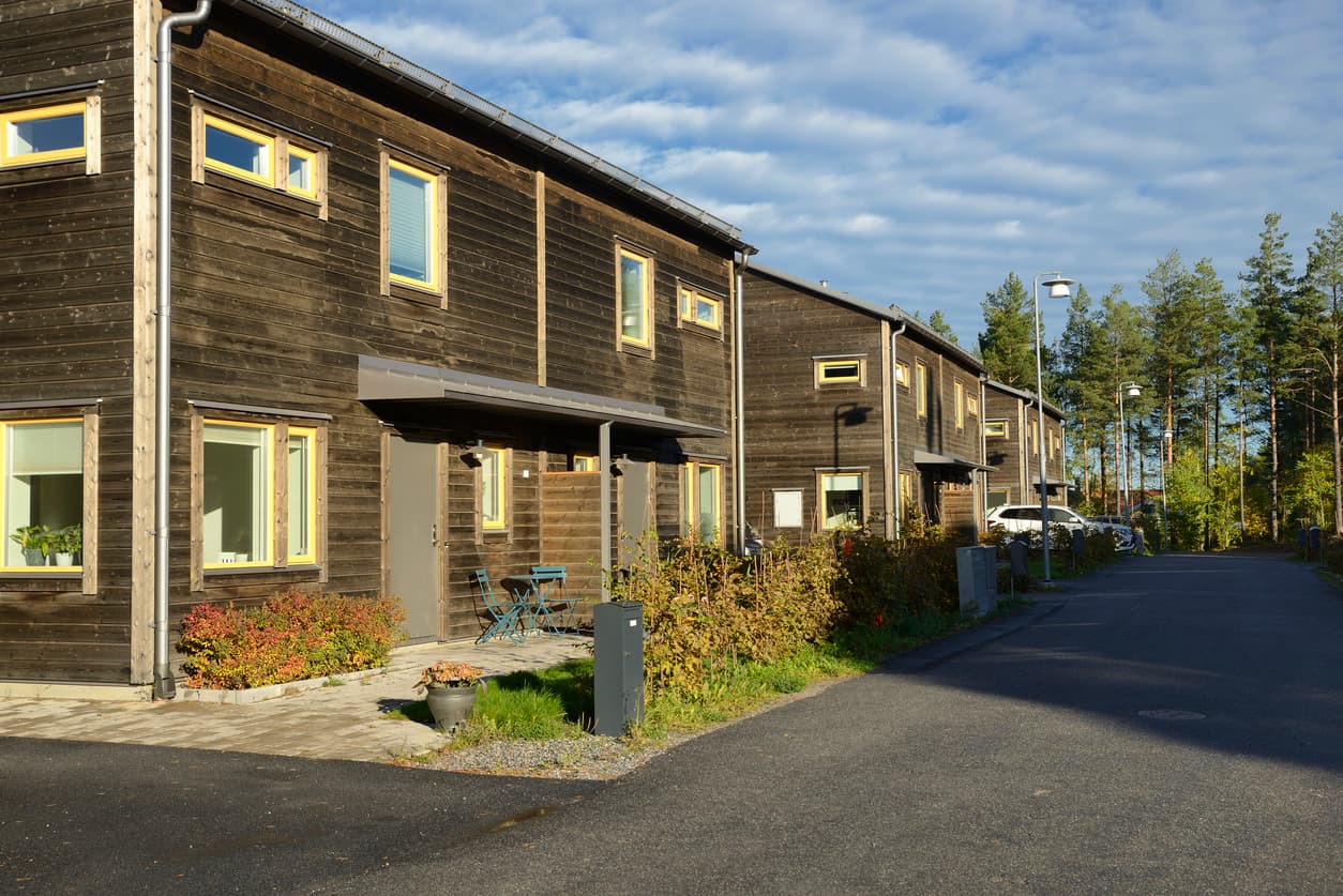 Mørke trekledde rekkehus med gule vinduskarmer og små private uteplasser mot veien, brukt som illustrasjon i artikkel om eksklusiv bruksrett i sameie.