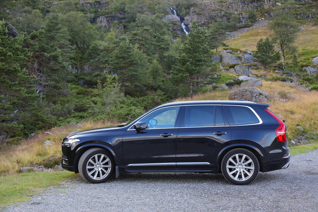 Svart SUV parkert på grusplass foran fjellside med foss i Norge, brukt som illustrasjon i artikkel om at selger nekter å heve bilkjøpet.