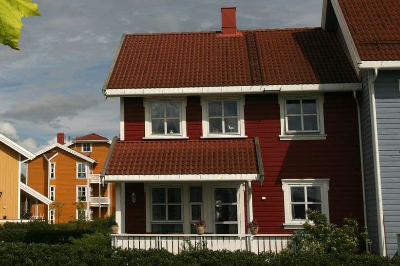 Rødt rekkehus med teglsteinstak, hvite vinduer og veranda, brukt som illustrasjon i artikkel om innboforsikring og muggsopp.