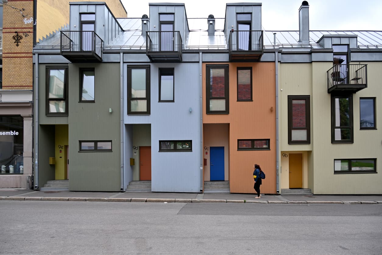 Fargerike rekkehus i grønt, blått, oransje og gult med balkonger og nummererte dører, brukt som illustrasjon i artikkel om sameie og regler.