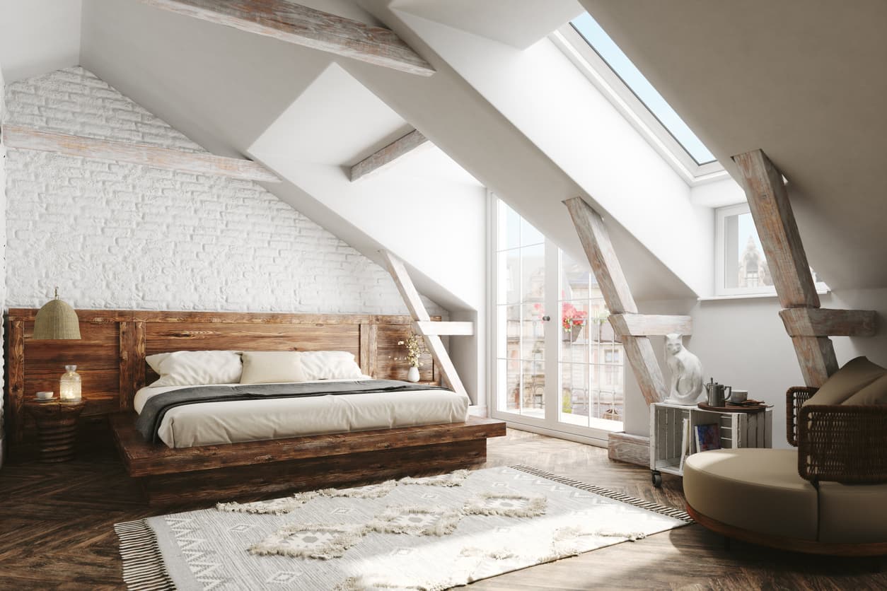 Innredet loftssoverom med seng, skråtak, synlige takbjelker og store takvinduer, brukt som illustrasjon i artikkel om godkjent bruk etter renovering.