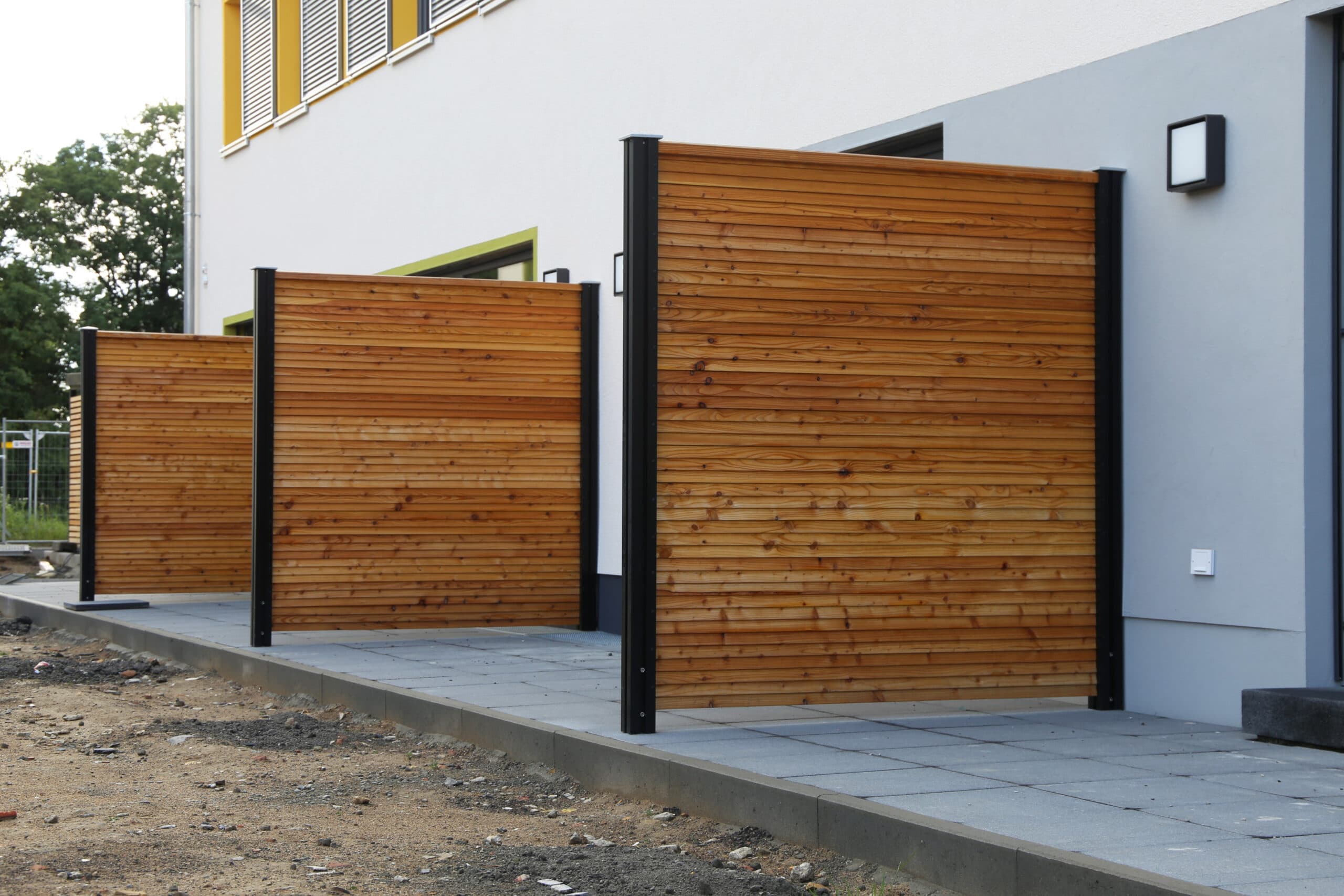 Levegg mot nabo mellom terrasser i et moderne boligområde.